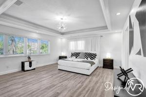 a white bedroom with a bed and a chandelier at 7 BR Intercostal Beauty with Heated Pool in Hallandale Beach +89 photos