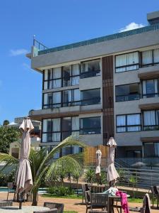 a building with tables and umbrellas in front of it at Flat na BeiraMar com Piscina Privativa in Porto De Galinhas +25 photos