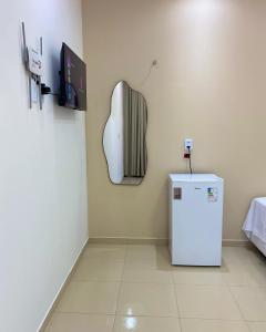 a room with a refrigerator and a tv on the wall at Suite no Centro da Praia de Flecheiras in Trairi