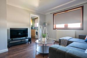 ein Wohnzimmer mit einer blauen Couch und einem Fernseher in der Unterkunft Mercer Apartment in Alloa