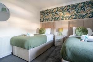 ein Schlafzimmer mit zwei Betten mit grüner Bettwäsche in der Unterkunft Mercer Apartment in Alloa