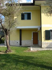 una casa gialla con una porta e un albero di Azienda Agricola Carbone Cosimo a Montecorvino Pugliano