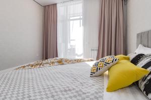 a bedroom with a bed with yellow pillows and a window at Aruna Deluxe Apartment идеально для туриста in Astana