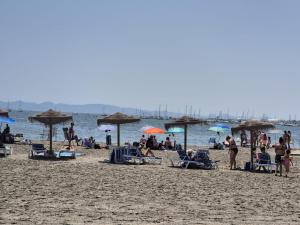 eine Gruppe von Menschen mit Sonnenschirmen an einem Strand in der Unterkunft Casa Flamingo - Corner house near beach & boulevard with sea & salt lake view in San Pedro del Pinatar