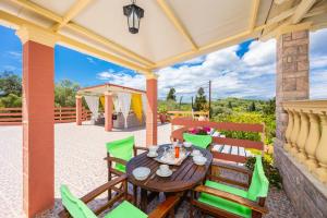 eine Terrasse mit einem Holztisch und grünen Stühlen in der Unterkunft Villa Psaropouli in Dragotiná