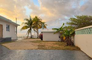 a driveway to a house with palm trees and the ocean at Ventana Va1c at Arecibo 681 Ocean Drive in Arecibo