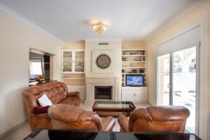 Una sala de estar con muebles de cuero y chimenea. en Villa CARMENÇÓ, en Castelló d'Empúries