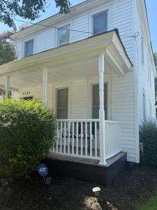 a white house with a porch with a dog on it at Relaxation & Peace in Newport News