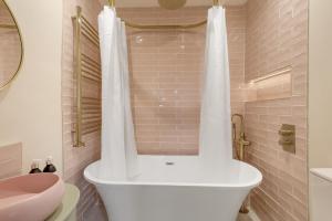 eine weiße Badewanne im Bad mit Waschbecken in der Unterkunft Mill Cottage - North East Escapes in Belford + 23 Fotos