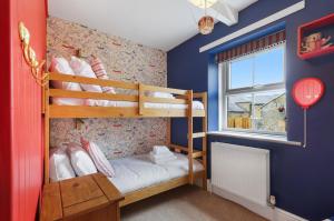 ein Schlafzimmer mit zwei Etagenbetten und einem Fenster in der Unterkunft Mill Cottage - North East Escapes in Belford