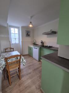 a kitchen with a table and a kitchen with green cabinets at Petite maison avec jardin à Bagnoles de l'Orne in Bagnoles de l'Orne