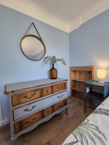 a bedroom with a dresser with a mirror and a table at Petite maison avec jardin à Bagnoles de l'Orne in Bagnoles de l'Orne