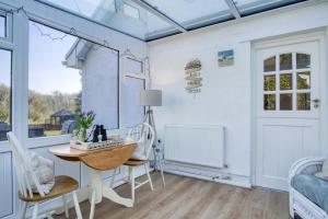 una stanza con un tavolo, delle sedie e una finestra di The Willows - 2 Bedroom Cottage - Oxwich a Oxwich