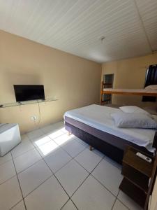 a bedroom with a bed and a flat screen tv at Pousada Buenos Aires in Pontal do Paraná