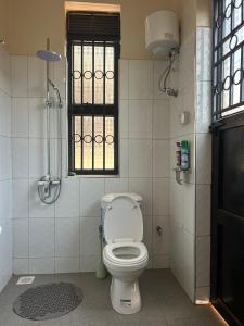 a bathroom with a toilet and a window at Seil Apartment in Kampala