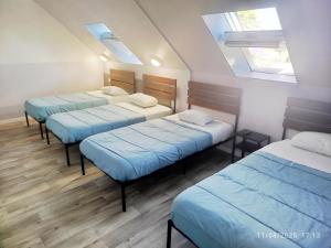 three beds in a room with blue sheets at ENOR Hôtel - Guingamp in Saint-Agathon