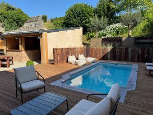 a patio with a pool and chairs and a wooden deck at Maison Eudoise, piscine et spa in Eu