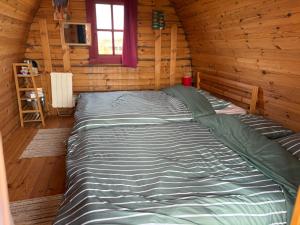 een groot bed in een blokhutslaapkamer bij Terres du Calvados 