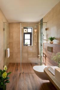 a bathroom with a tub and a glass shower at Greenfield · 3BHK Portuguese Villa in Assagao Goa in Goa