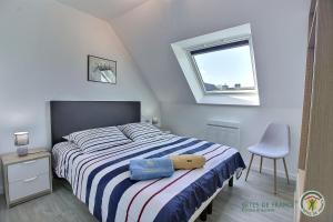 ein Schlafzimmer mit einem Bett, einem Stuhl und einem Fenster in der Unterkunft Les agapanthes in Perros-Guirec