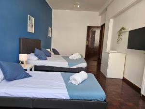 una stanza con tre letti con pareti blu e una tv di Blife Tonya - private rooms at Santantonya 1st floor a Faro