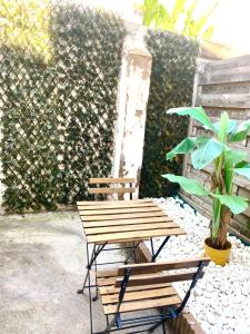 a wooden bench and a table and a plant at Le Cocon Caché in Valenciennes +1 photo