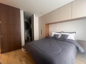 ein Schlafzimmer mit einem großen Bett mit grauer Bettwäsche in der Unterkunft Bogotá Centro, Cerca de Monserrate y La Candelaria, Apartamento Moderno con Terraza panorámica, 2 habitaciones in Bogotá
