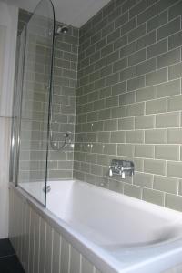 a white bath tub in a bathroom with green tiles at Wee Corsee in Nairn