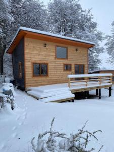 a log cabin with a bench in the snow at Mini Casa a 6 kilómetros de Villa Cerro Castillo Aysen Carretera Austral in Villa Cerro Castillo