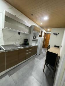 a kitchen with a sink and a table and a refrigerator at Residencial Refugio do Mar in Florianópolis