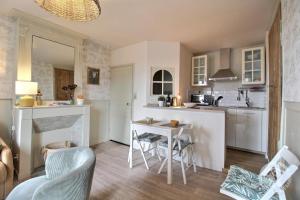 a kitchen with white cabinets and a table and chairs at La terrasse du champ clos in Dinan