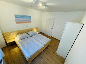 a bedroom with a bed and a white wall at Ferienwohnung Bad Camberg - Apartment Baumwipfel in Bad Camberg