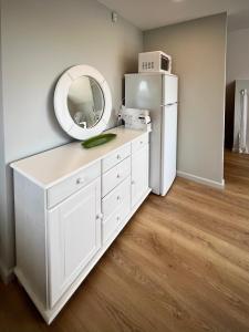 a white dresser with a mirror and a refrigerator at Lejnieki Apartment 4 in Pape +61 photos