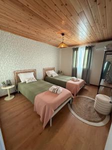 a bedroom with two beds and a wooden ceiling at Family Home - Alojamento Local in Nordeste