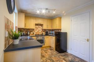 a kitchen with wooden cabinets and a black refrigerator at Merriotts Court - Parking - WIFI in Newport +14 photos