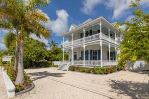 a white house with a palm tree in front of it at FUENTE at Azul Mansion Key West in Key West