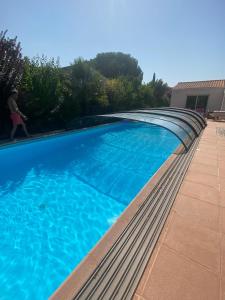 a large blue swimming pool with a person walking around it at Villa avec jardin et piscine 3 minutes de la Rochelle in Lagord