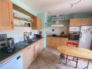 a kitchen with wooden cabinets and a table in it at Villa avec jardin et piscine 3 minutes de la Rochelle in Lagord