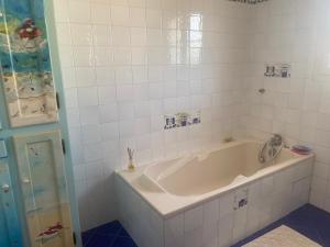 a white bath tub in a white tiled bathroom at Villa avec jardin et piscine 3 minutes de la Rochelle in Lagord +9 photos