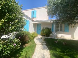 a white house with blue shutters and a yard at Villa avec jardin et piscine 3 minutes de la Rochelle in Lagord