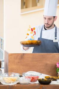 a chef is holding a dish of food at Atrium Hotel Thassos in Potos