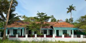马拉利库兰Coconut Bay Marari的一座拥有绿色屋顶和棕榈树的房子