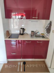 a kitchen with red cabinets and a sink at Le Thalassa I appartement T2 en bord de plage et du Port in Gruissan