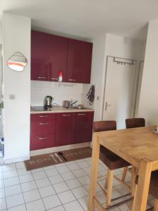 a kitchen with red cabinets and a wooden table at Le Thalassa I appartement T2 en bord de plage et du Port in Gruissan