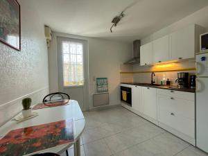 a kitchen with white cabinets and a table in it at Cosy one bedroom flat with terrace in Saint-Lunaire