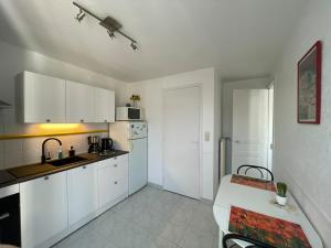 a kitchen with white cabinets and a table in it at Cosy one bedroom flat with terrace in Saint-Lunaire