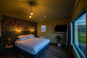 a bedroom with a bed and a large window at Wild Hideaways Luxury Lodges and Eco Spa in Bantry