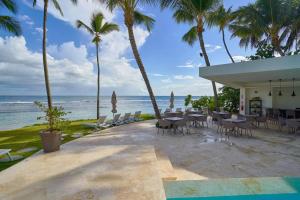 a restaurant on the beach with palm trees and the ocean at Beachfront FL21 Con Tina Aquarella in La Puntica de Juan Dolio
