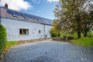 ein weißes Gebäude mit Sonnenkollektoren auf dem Dach in der Unterkunft The Barn on Loch Tay - Hot Tub in Lawers