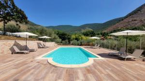 a swimming pool with chairs and umbrellas on a wooden deck at Villa MaVi Guesthouse in Maenza